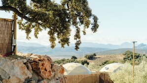A rustic outdoor setting with stone walls, a wooden fence, and a view of distant mountains.