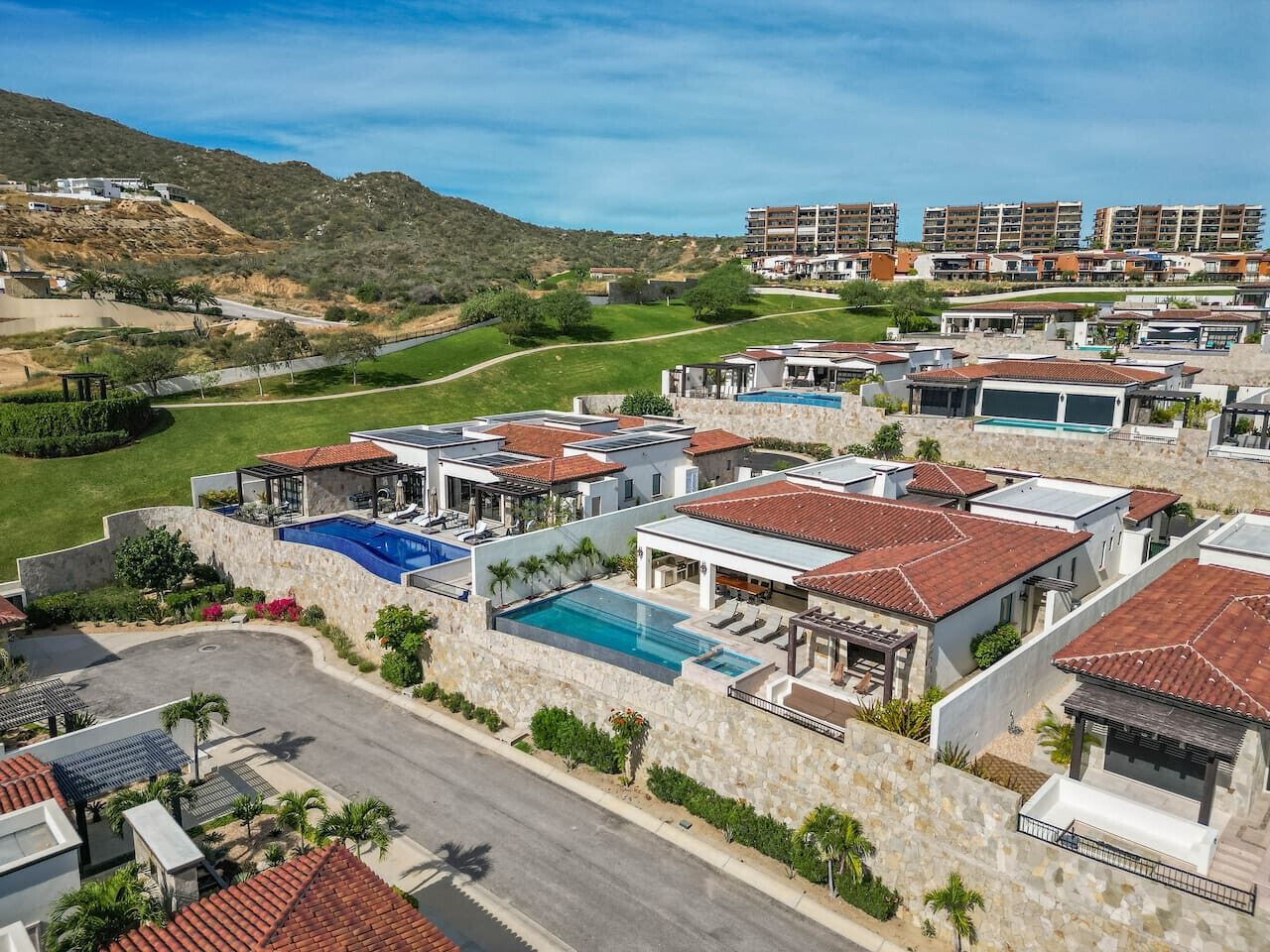 Un quartier résidentiel avec des maisons modernes, une piscine et, au loin, un paysage vallonné.