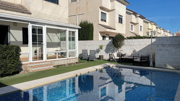 A residential pool with a glass-enclosed patio area, a small lawn, and a brick wall. - Villa for 4 people by the sea (Daimús)
