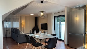 A modern kitchen with a dining area, featuring a large table set for four, a built-in oven, and a sleek refrigerator. - Villa for 4 people by the sea (Daimús)