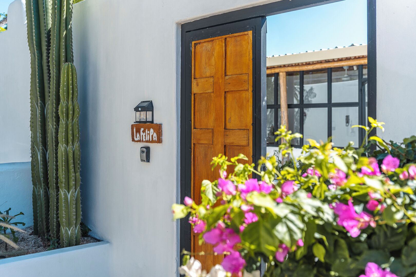 Entrada d'un edifici amb una porta de fusta, un rètol que diu "La Felipa" i una planta de cactus.