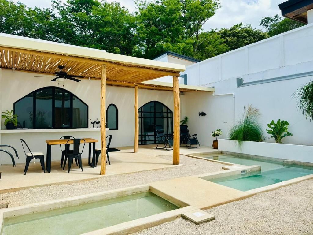 Eine moderne Terrassenanlage mit Pool, Holz-Pergola und Sitzbereich.