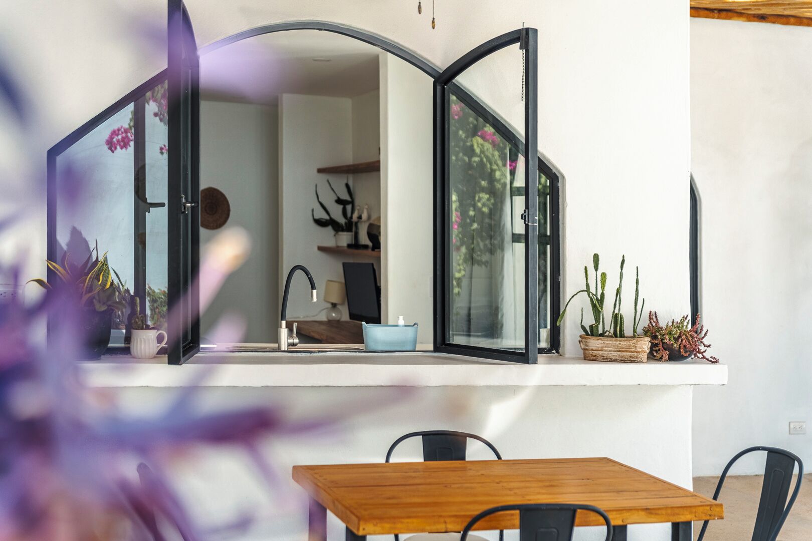 A modern kitchen with a large window, a sink, and a wooden table.