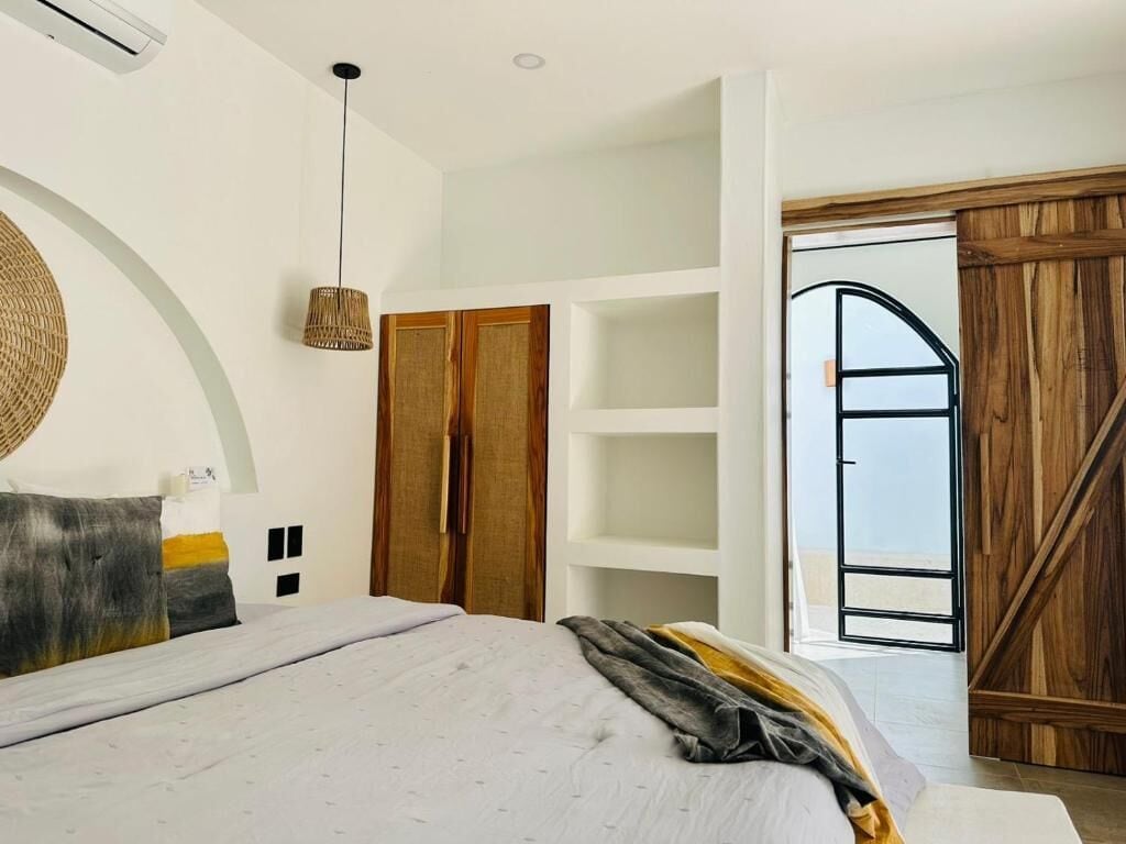 Un dormitorio con cama, armario, lámpara colgante y puerta que da a un espacio exterior.