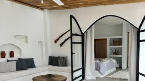 Una habitación moderna con un sofá blanco, una mesa redonda de madera y un ventilador de techo.