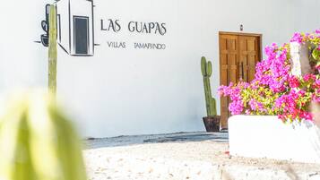 Un muro bianco con la scritta "LAS GUAPAS VILLAS TAMARINDO" e una porta in legno.