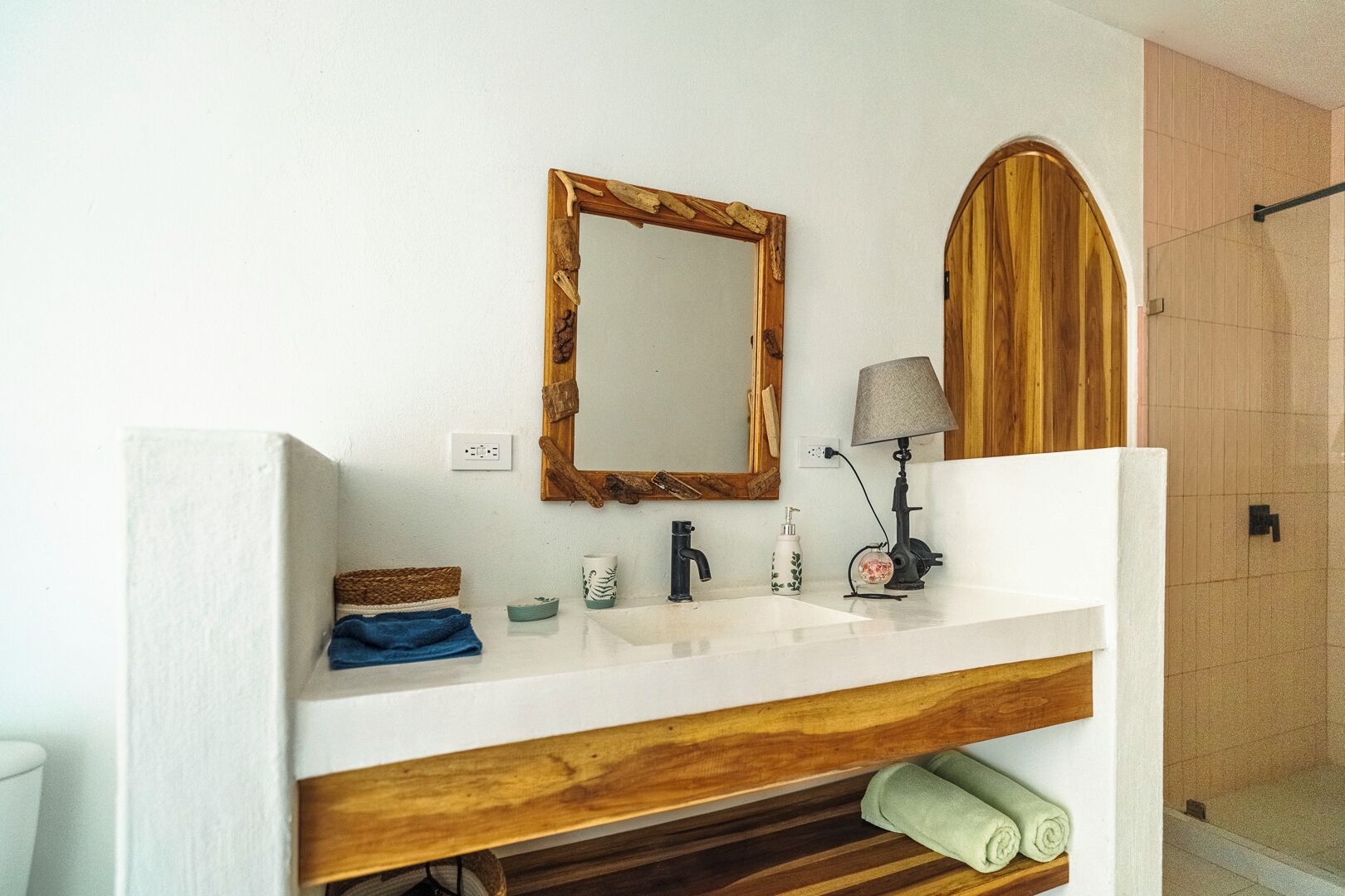 A bathroom with a wooden vanity, a mirror, a sink, a towel rack, and a shower area.