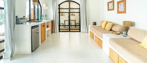A modern living room with a sofa, a dining area, and a kitchen.