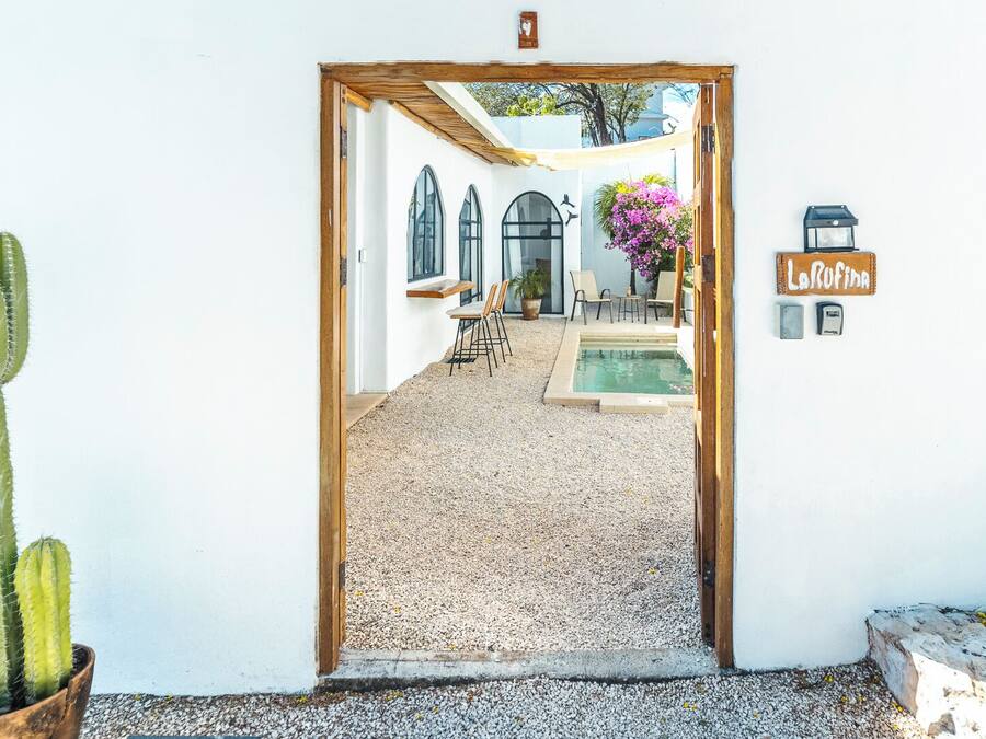 A doorway leading to a courtyard with a pool, seating area, and a cactus plant.