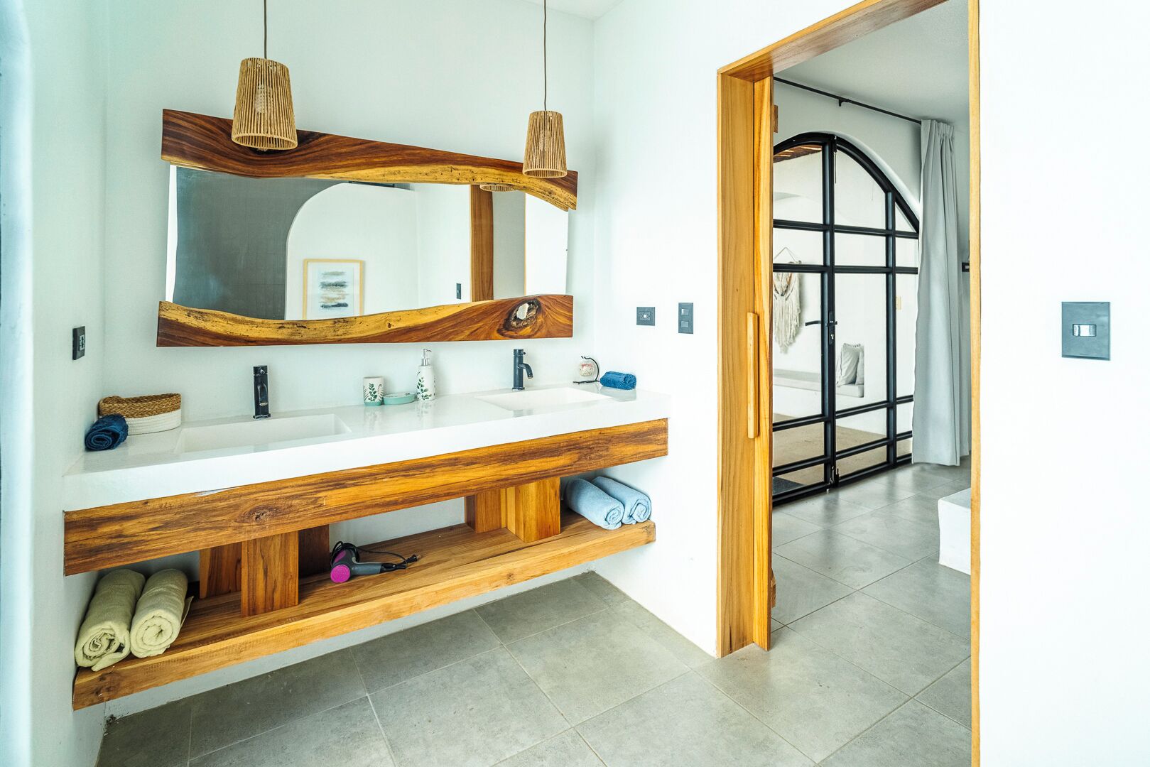 Un baño moderno con tocador de madera, dos lavamanos y un espejo grande.