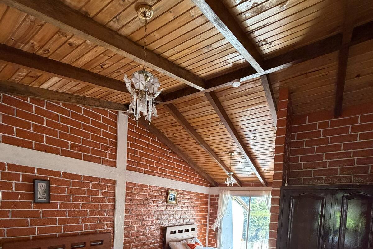Una stanza con due letti in legno, un muro in mattoni, un soffitto in legno e un ampio guardaroba.
