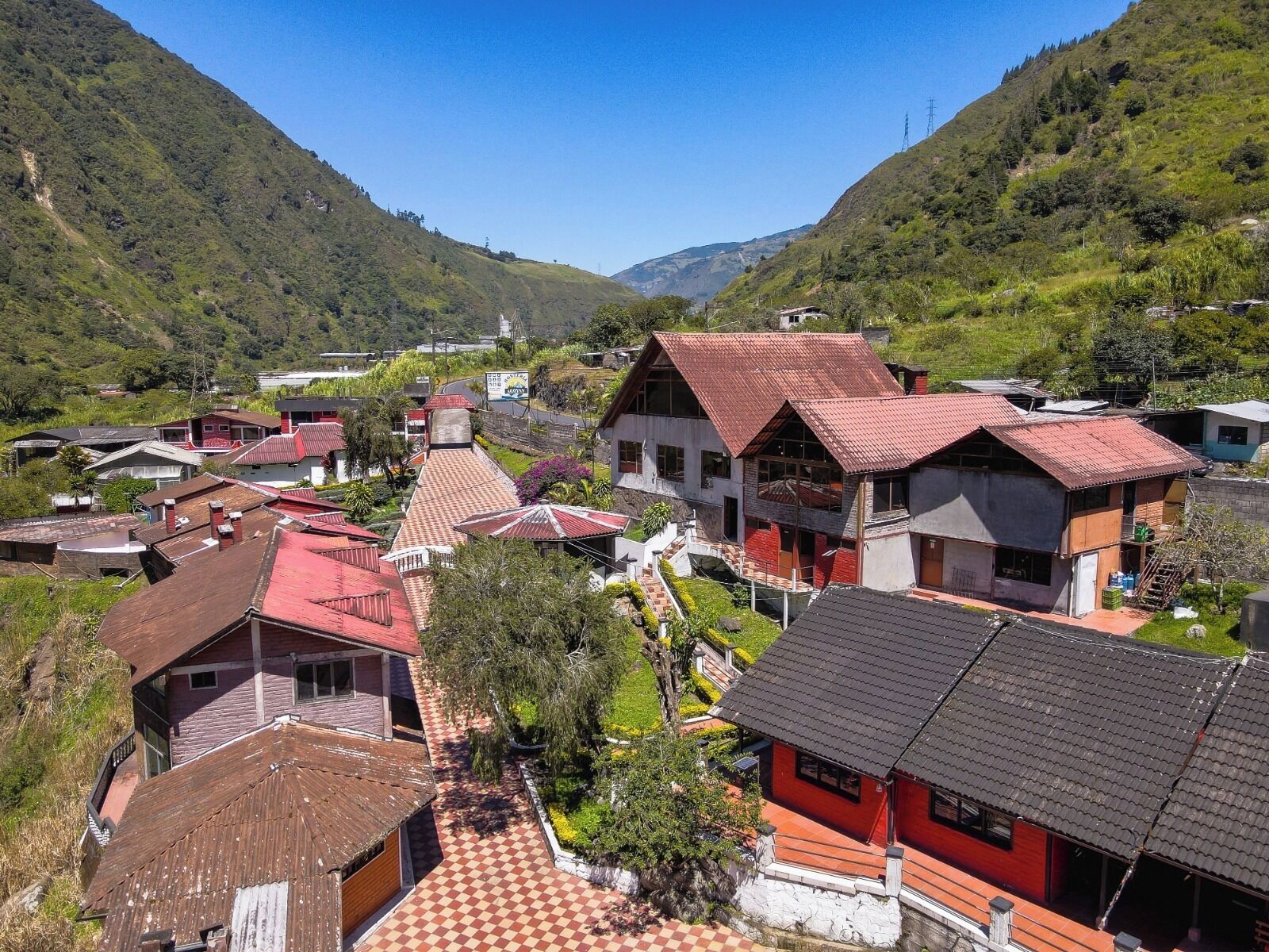 Un village doté de maisons traditionnelles, d’un bâtiment central coiffé d’un toit rouge et entouré de verdure.
