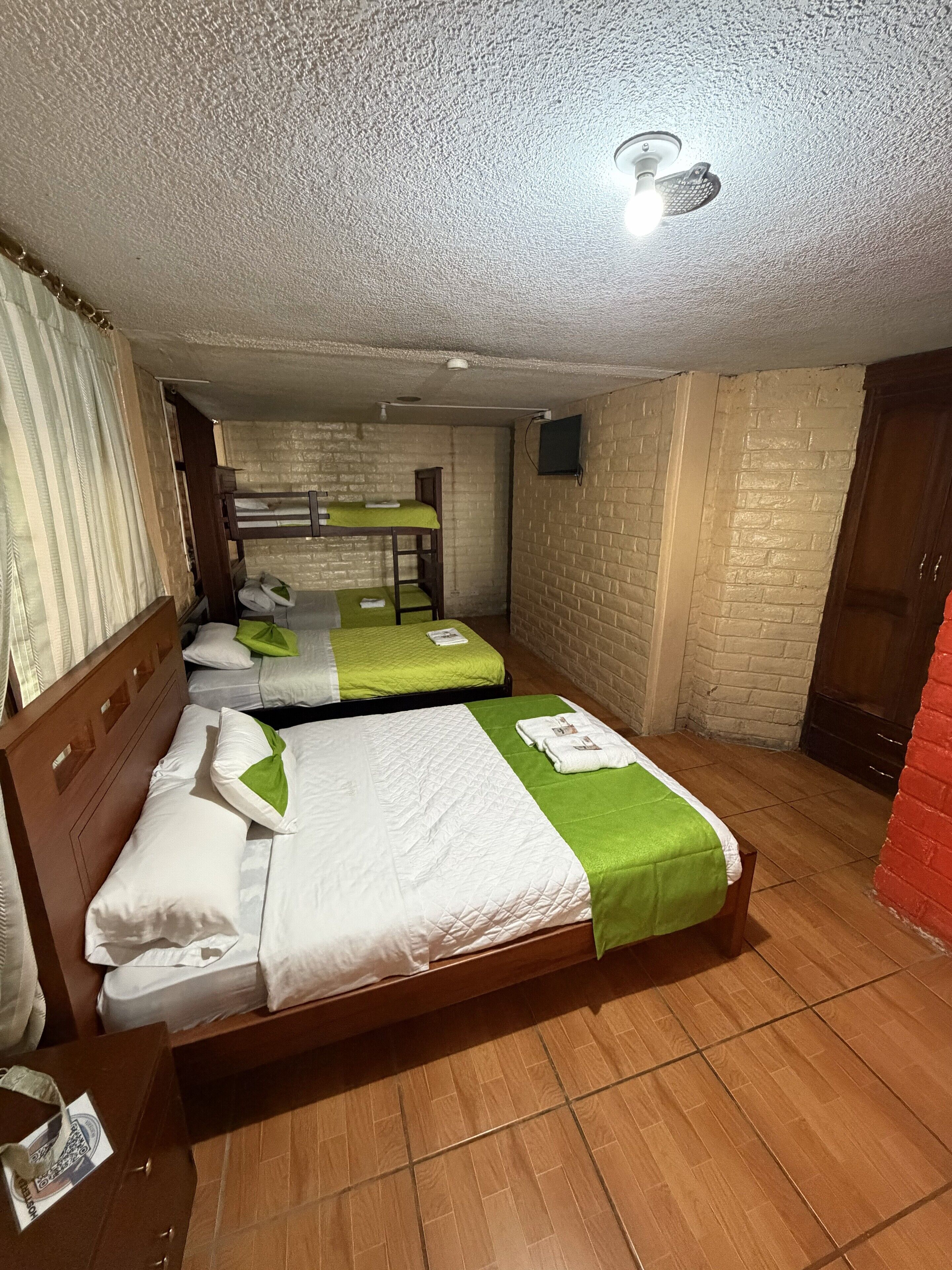 Une chambre d’hôtel avec des lits superposés, un téléviseur à écran plat et un ventilateur de plafond.