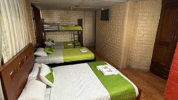 Une chambre d’hôtel avec des lits superposés, un téléviseur à écran plat et un ventilateur de plafond.