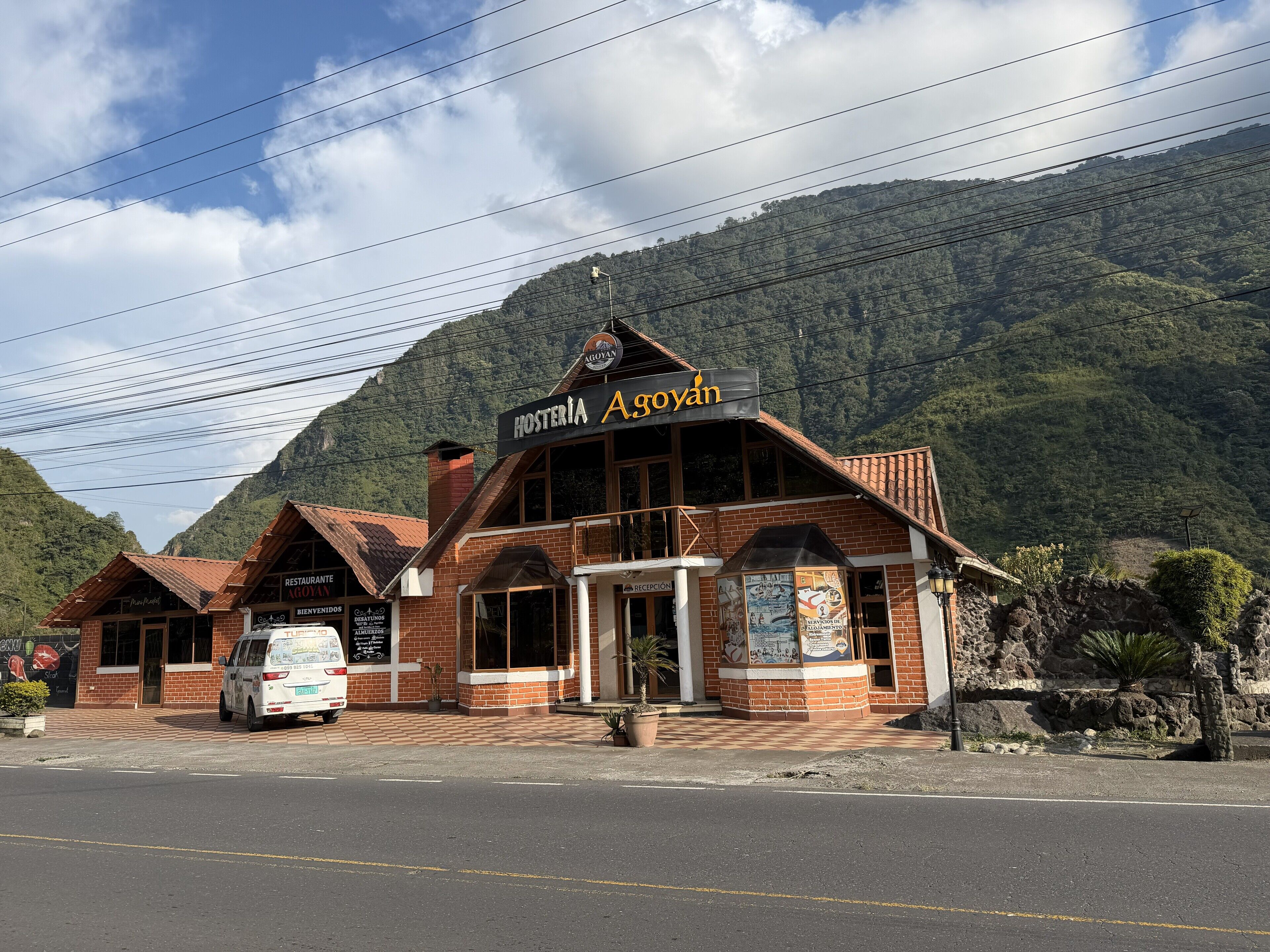 Un edificio de ladrillo con un letrero que dice "Hostería Agoyán" y una zona de recepción.