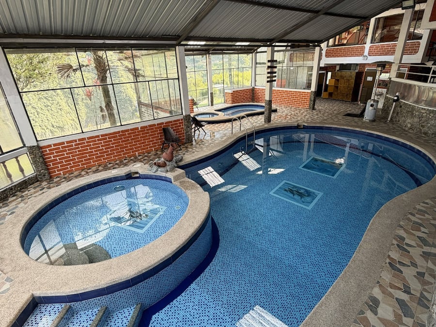 Une piscine intérieure avec un sol carrelé et un espace équipé d’un jacuzzi.