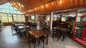 Ein Restaurant mit Holztischen und -stühlen, einer Treppe und einem Coca-Cola-Kühlschrank.