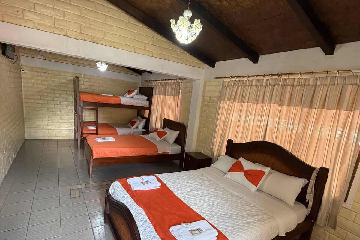 Una stanza con un letto a castello, un letto singolo e una testiera in legno.