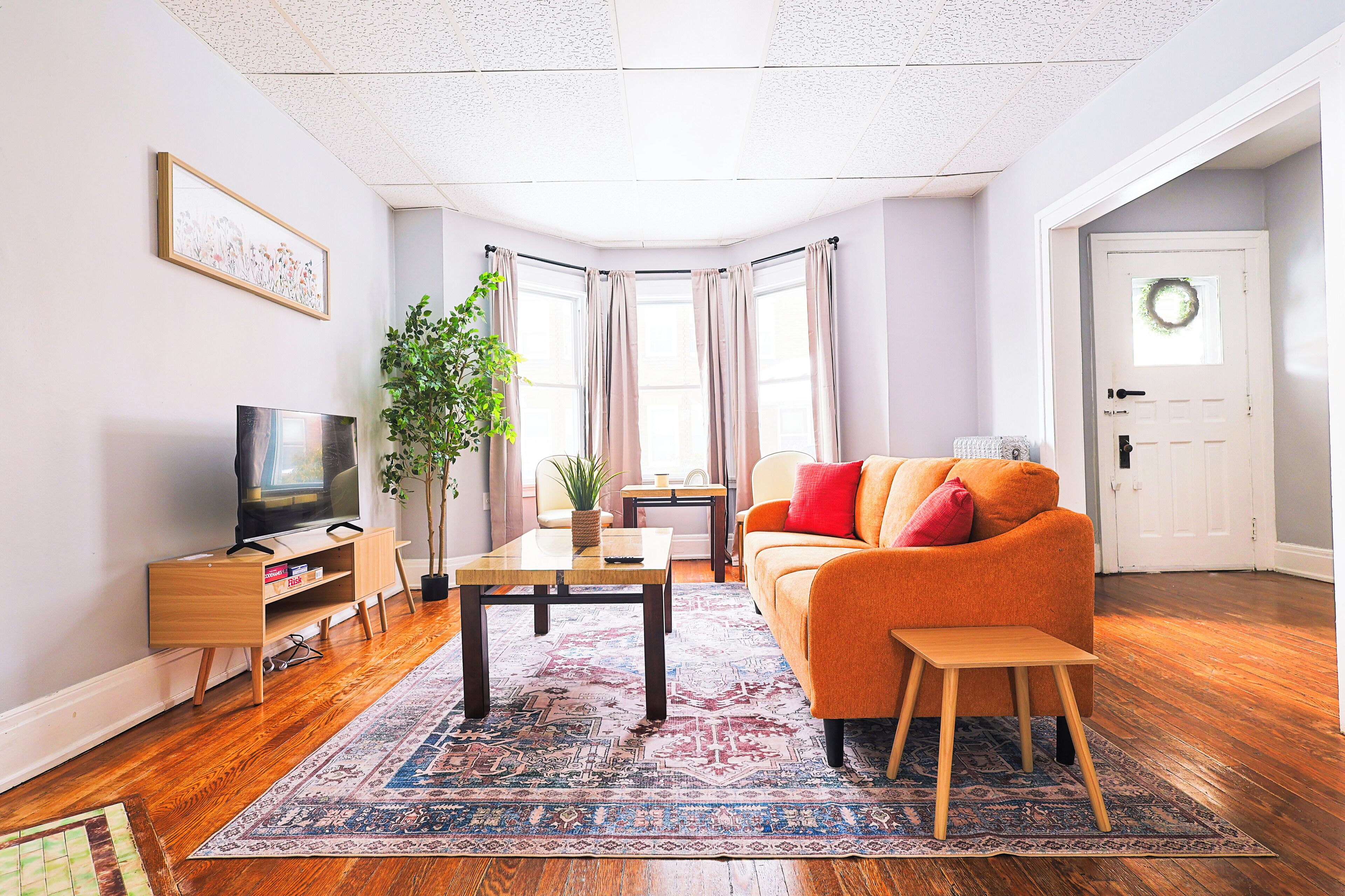 Ein Wohnzimmer mit einer Couch, einem Couchtisch, einem Fernseher und einer Pflanze.