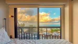 Camera da letto con una grande finestra vista spiaggia e parcheggio.