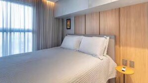 Camera d'albergo moderna con un letto grande, una testiera in legno e un tavolino con una lampada.