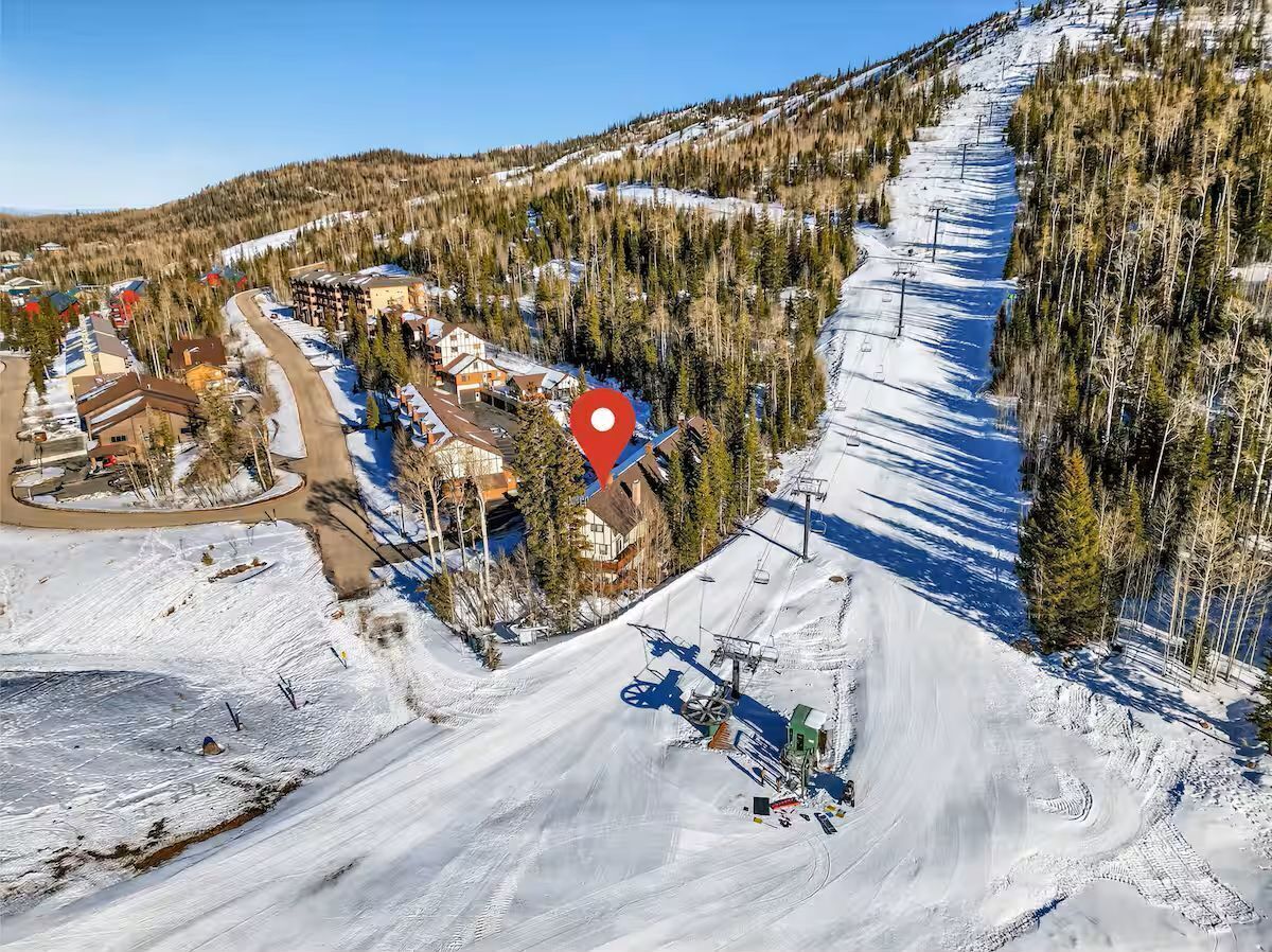 A ski resort with a ski lift, buildings, and a snow-covered landscape.