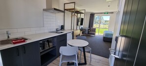 A modern kitchen with a sink, stove, and dining area with chairs and a table.