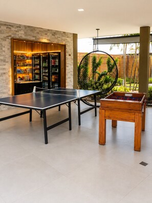 Una mesa de ping pong, una mesa de futbolín y un bar de aperitivos con estantes llenos de bocadillos y bebidas.