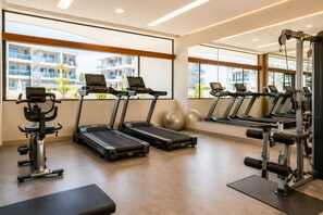 Uma academia com esteiras, bicicletas ergométricas e máquinas de musculação.