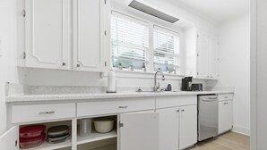 A modern kitchen with white cabinetry, a granite countertop, a built-in oven, and a dishwasher. - Charming 2BR Retreat in North Little Rock, Close to Hospitals & Downtown (North Little Rock)