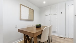 A dining area with a wooden table, four chairs, a potted plant, and white walls. - Charming 2BR Retreat in North Little Rock, Close to Hospitals & Downtown (North Little Rock)