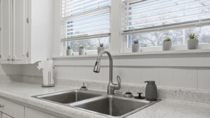 A kitchen with two stainless steel sinks, a white countertop, and a window with blinds. - Charming 2BR Retreat in North Little Rock, Close to Hospitals & Downtown (North Little Rock)