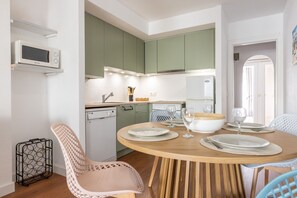 A modern kitchen with green cabinets, a microwave, and a dining table set for four. - Apartment at 260 m from the beach, recently renovated (L'Escala)