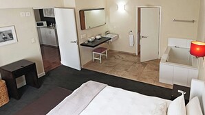 Een hotelkamer met een bed, bureau, badkamer en kitchenette.