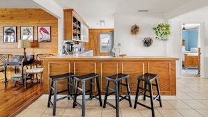 Una cocina con armarios de madera, una barra con taburetes y obras de arte colgadas en la pared.