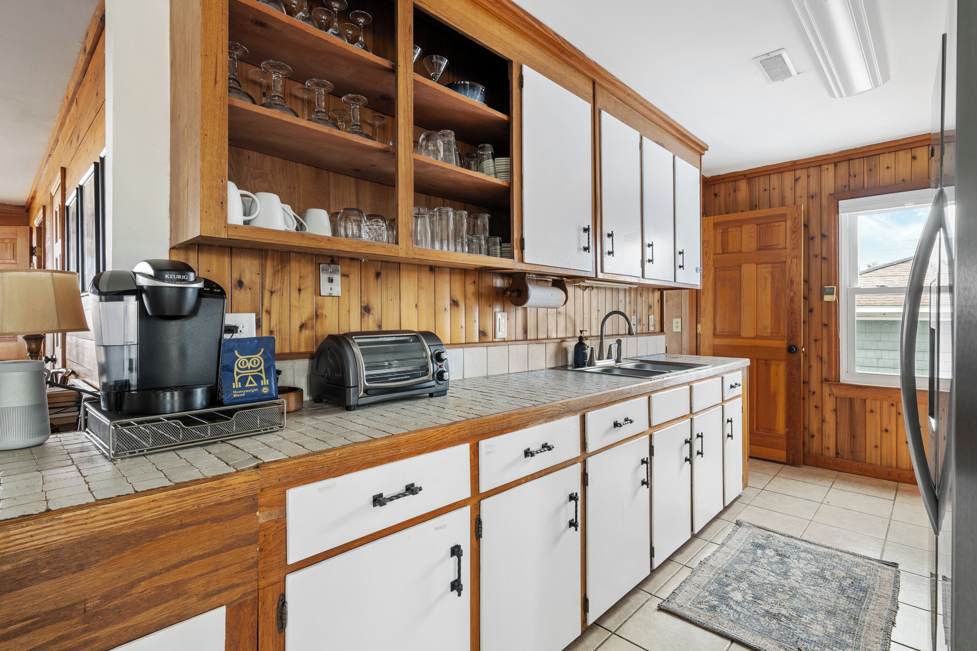 A kitchen with wooden cabinets, a built-in coffee maker, a toaster, and a sink.