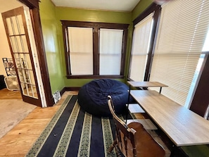 Una habitación con un sillón de mimbre, un banco de madera y una alfombra estampada.