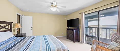 Un dormitorio con cama, cómoda, televisor y balcón con una silla.