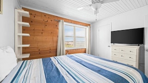 Een slaapkamer met een bed, een houten garderobe, een televisie en een raam met gordijnen.