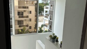 Ein modernes Zimmer mit großem Fenster, einer Kandelaberleuchte und einer kleinen Pflanzengruppe.