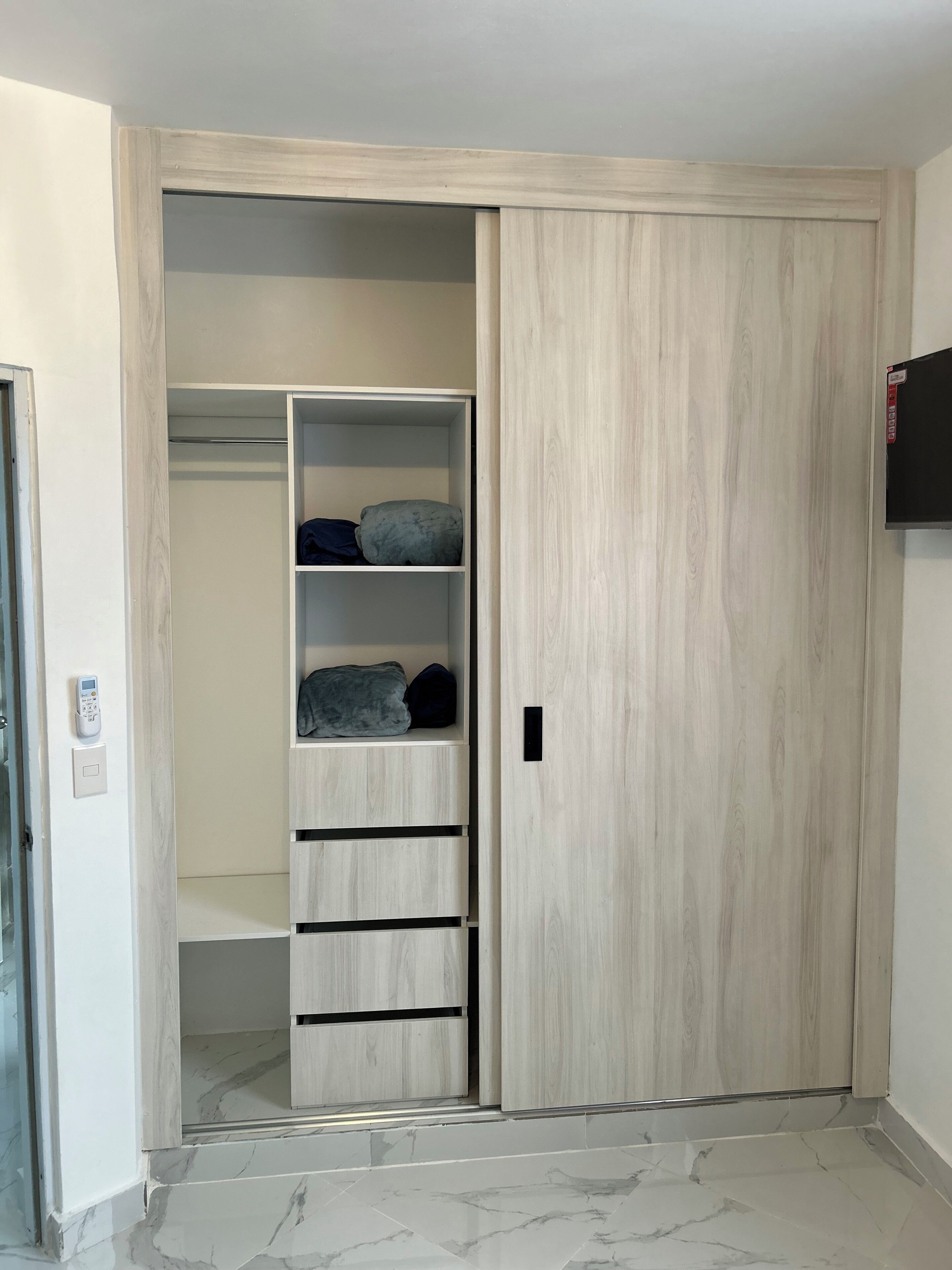 Ein begehbarer Kleiderschrank mit Schiebetür, eingebauten Regalen und Marmorfliesen.