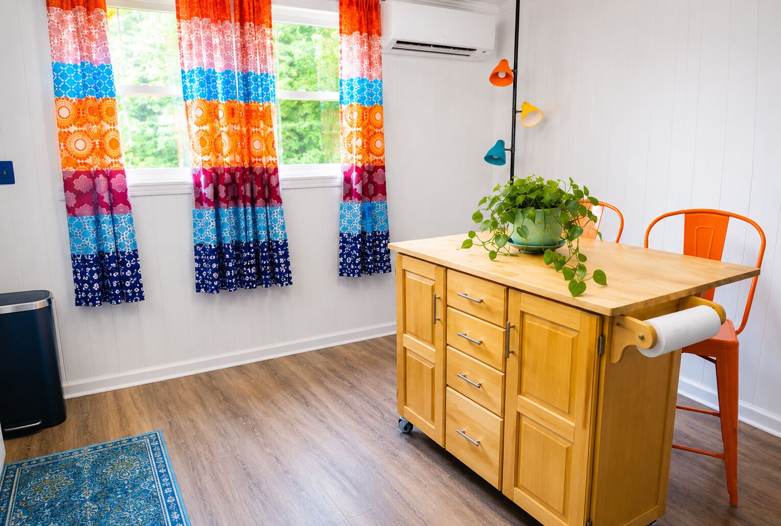 A room with a wooden cabinet, a chair, a plant, colorful curtains, and a window with an air conditioner.
