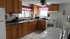A kitchen with wooden cabinets, a refrigerator, a microwave, a stove, and a washing machine.