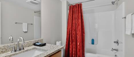 Un baño con lavamanos, espejo, ducha e inodoro.