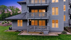 Une maison à deux étages dotée d’un balcon, de grandes fenêtres et d’une pelouse bien entretenue.