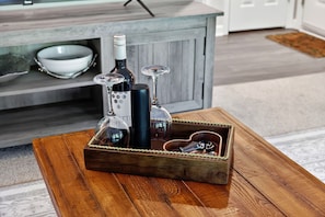 A wooden tray with bottles and glasses on a table.
