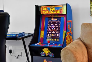 Une borne d’arcade Pac-Man avec un jeu de labyrinthe, un joystick rouge et un écran d’affichage des scores.