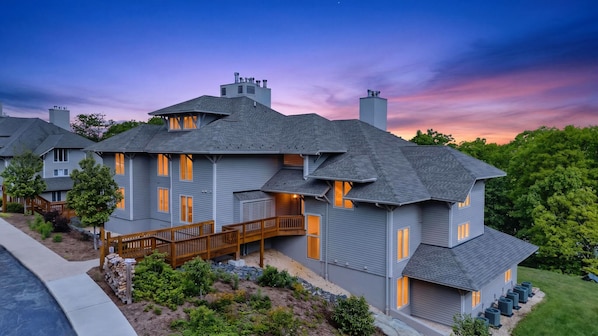 A modern two-story house with a balcony, a deck, and a well-maintained garden.