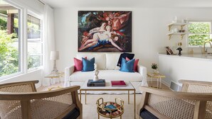 A living room with a white sofa, a painting, and a coffee table.