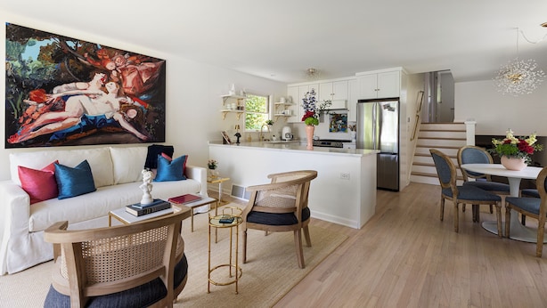 A modern living room with a sofa, chairs, and a dining area.